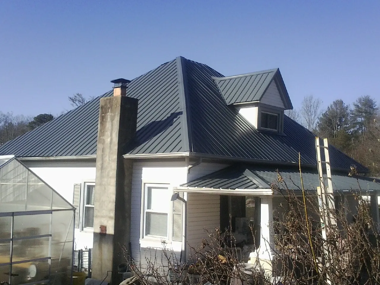 Dark blue standing seam metal roof on a white farmhouse with dormer — Slate & Tile Roof Repair by Roofing Brothers in Oregon City