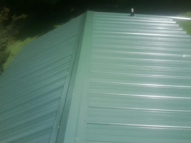 New green metal panels meeting at the ridge of a roof — Flat Roof Repair work by our crew in Oregon City