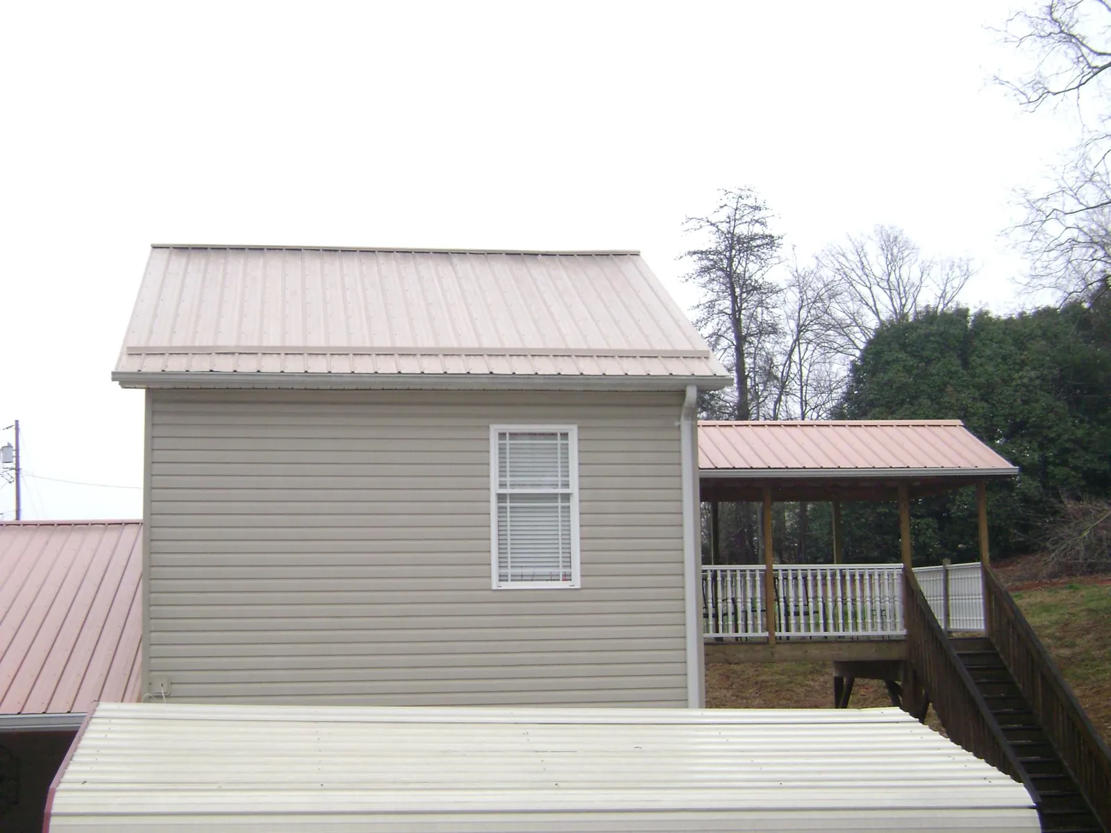 Tan metal roofs on a two story addition and attached porch, from a Roof Replacement job in Oregon City