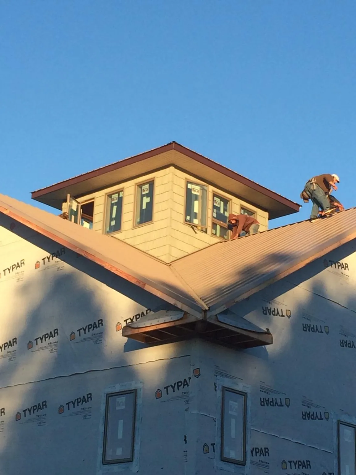 Roofers working around a rooftop cupola on a new metal roof at sunset — Roof Waterproofing in Oregon City by Roofing Brothers